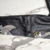 Close-up of black leather jacket sleeve with two white and gold embroidered eagle motifs